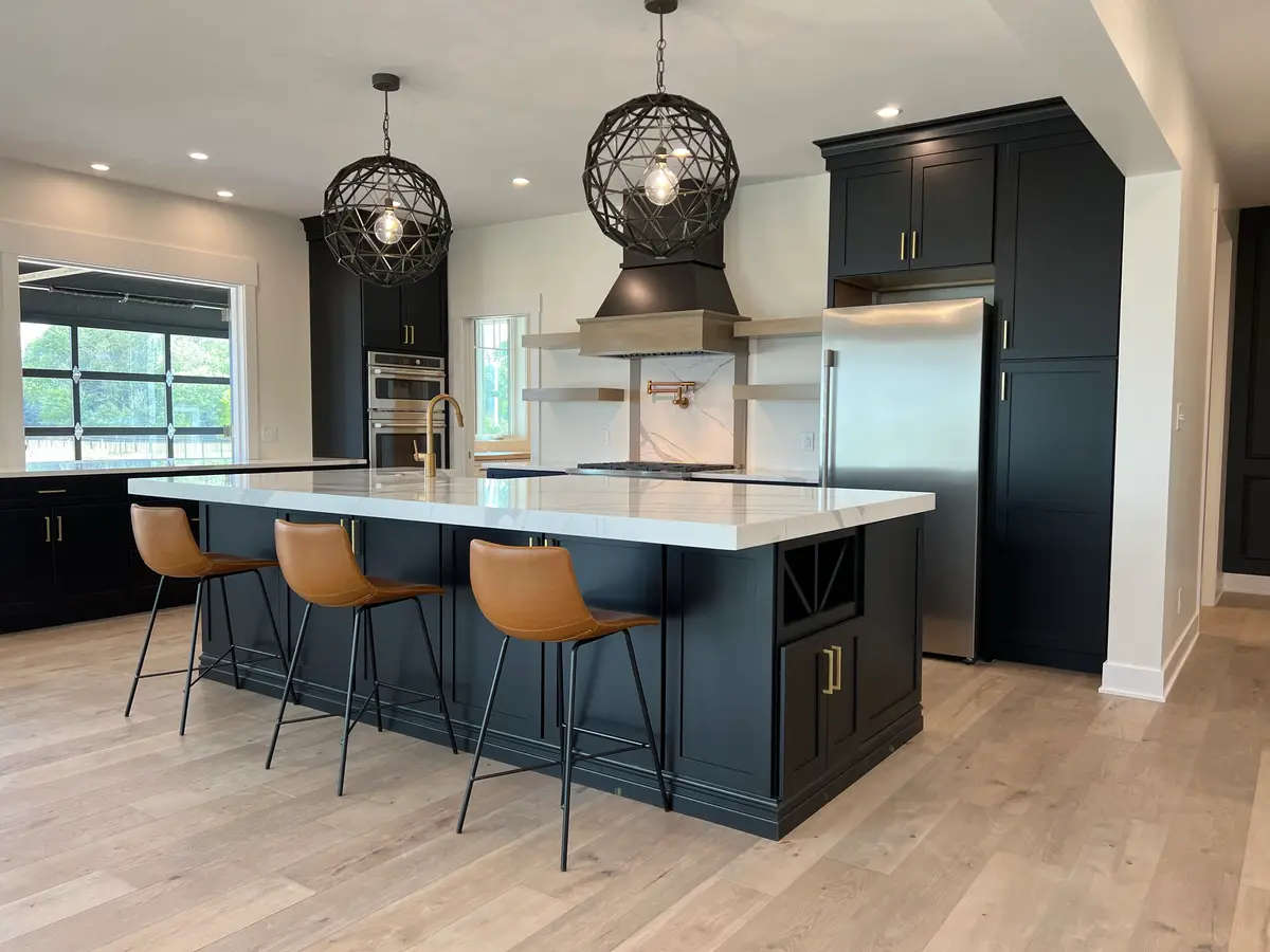 Black and white kitchen with quartz island, leather stools and orb pendants