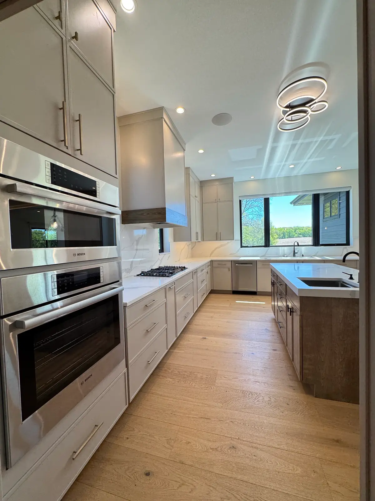 Modern kitchen with double wall ovens, taupe flat-panel cabinets and marble backsplash