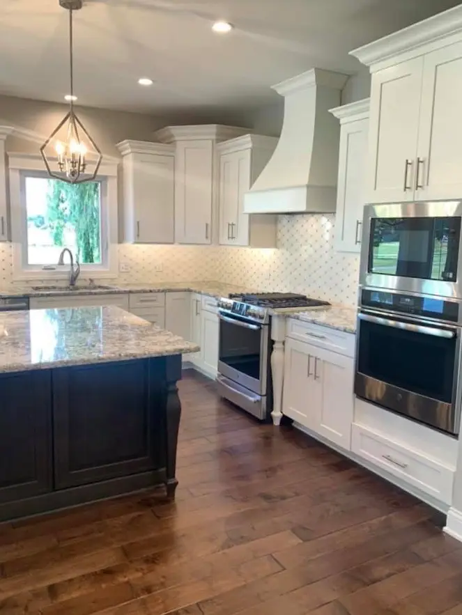 White kitchen with window over the sink and gas range under a white hood