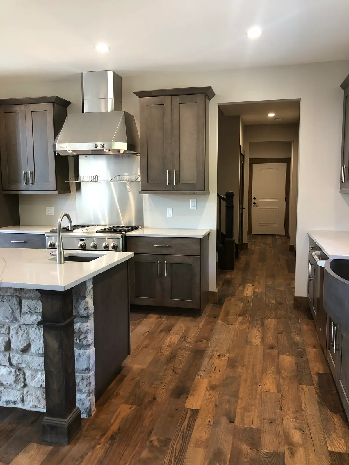 Gray shaker kitchen with stainless range hood and stone-wrapped island