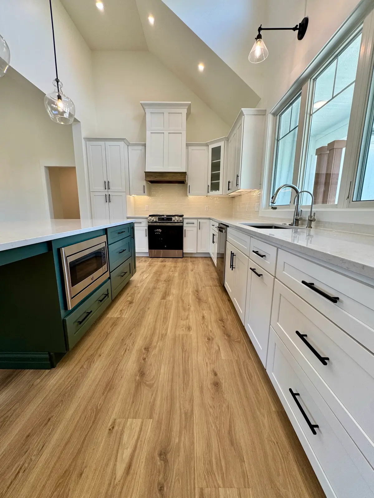 Green kitchen island with built-in microwave beside white shaker cabinets
