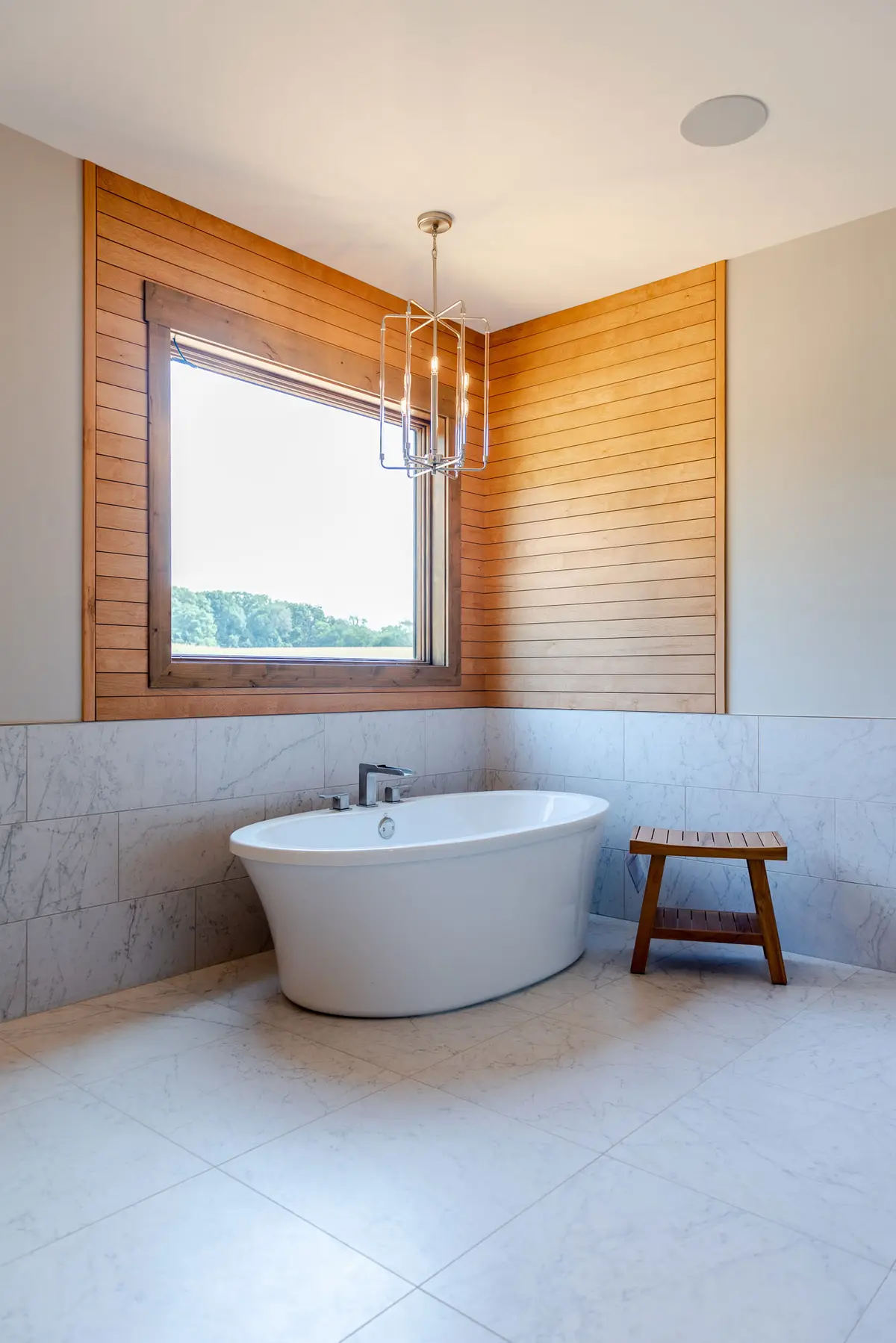 Freestanding tub beside a sunlit window