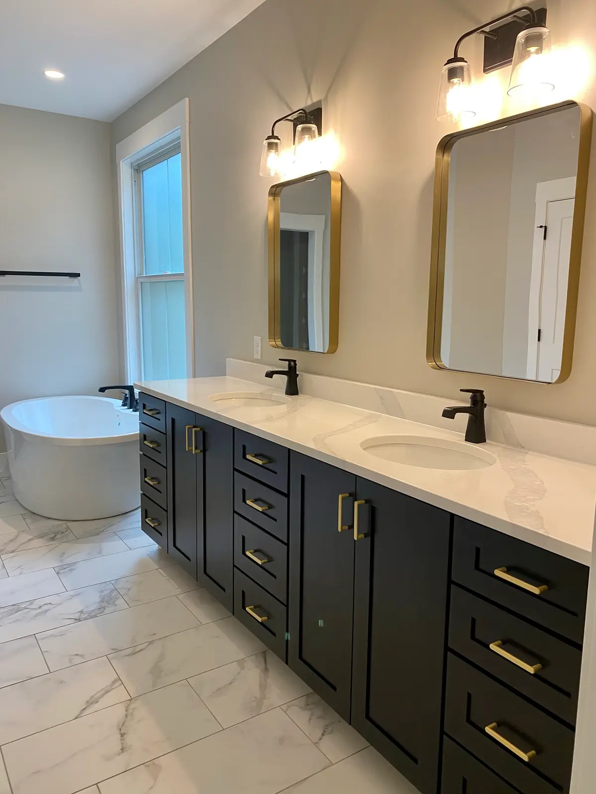 Master bath with freestanding tub, black double vanity and gold mirrors