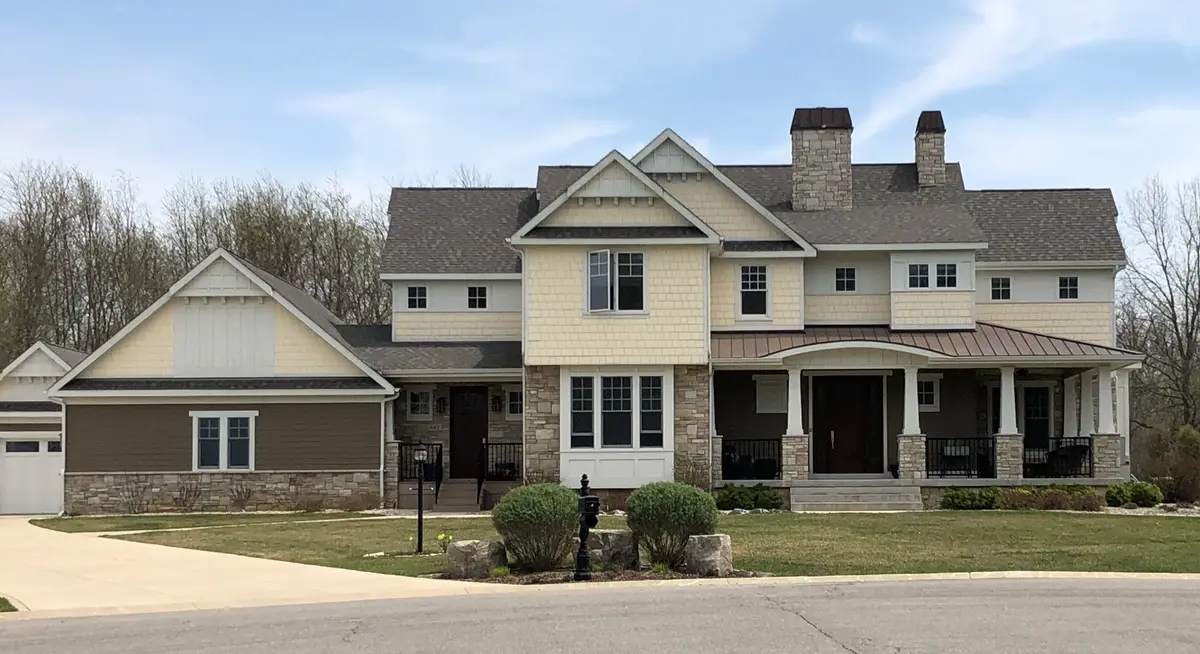 Cream shake craftsman with stone base, twin chimneys and columned porch