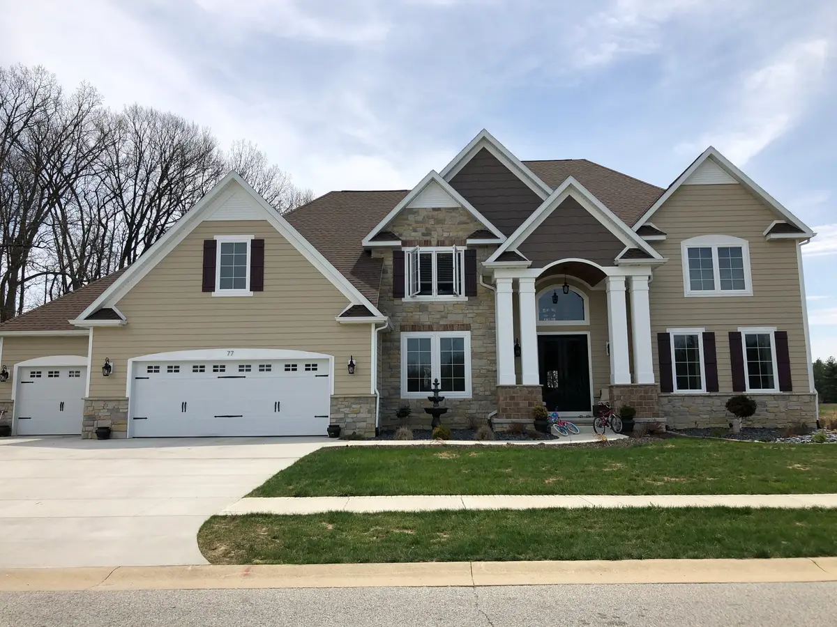 Tan two-story home with stone accents, arched entry and three-car garage