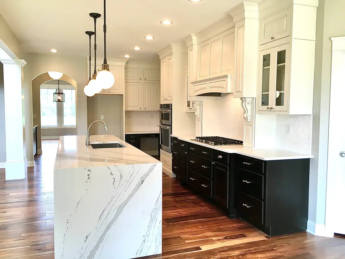 White kitchen with marble-look waterfall island and black cabinetry